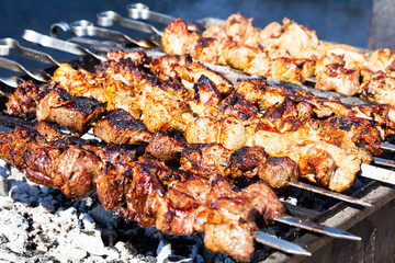 Grilled kebab cooking on metal skewer. Roasted meat cooked at barbecue. Traditional eastern dish,...