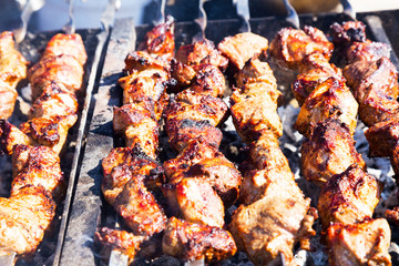Grilled kebab cooking on metal skewer. Roasted meat cooked at barbecue. Traditional eastern dish, shish kebab. Grill on charcoal and flame, picnic, street food