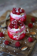 Selective focus. Healthy dessert in jars with curd cream and raspberries.