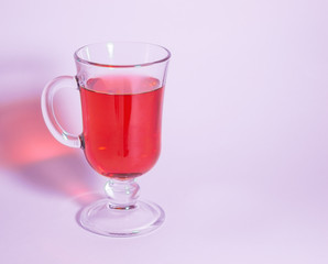 Red tea in a glass on a pink background