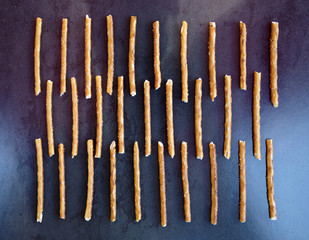 High angle view of pretzel sticks arranged on a dark background
