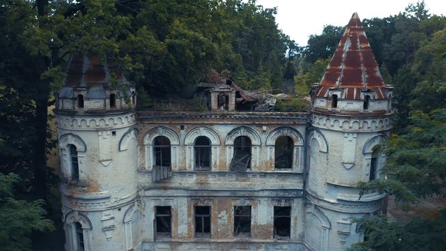 Abandoned 19th century palace or castle (manor or mansion house) with two towers and broken windows in Romanesque Revival architecture (or Neo-Romanesque) style. Aerial side view.