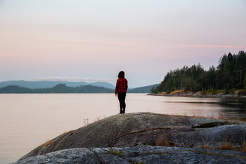 Girl Watching a Peaceful Sunrise on the Ocean Coast during Sunny Summer. Taken in Saltery Bay, Sunshine Coast, British Columbia, Canada.