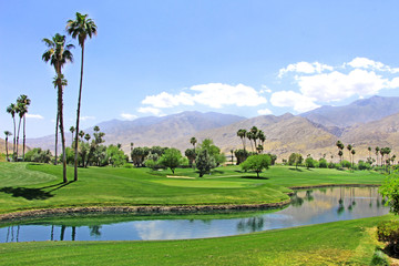 Green oasis in the desert - Golf course with palm trees and pond / river in Palm Spring.