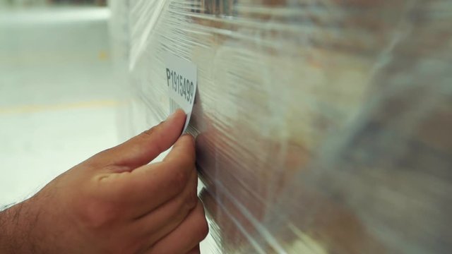 Close-up slow motion of hand sticking barcode on package.