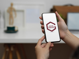 Female hands holding mock up smartphone in blurred office background