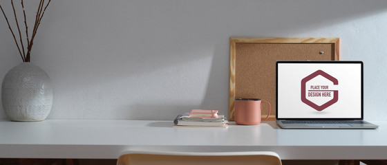 Workplace with mock up laptop, stationery, memory board, decoration and copy space on white desk