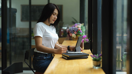 Portrait of female freelancer working with digital tablet on wooden bar