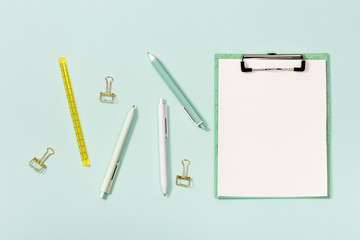 Flat lay with mock-up notebook and stationery for school or office. Blue and white colored pens, ruler and metal paperclips.