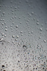 Rain droplet on window with cloudy sky