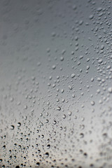 Rain droplet on window with cloudy sky