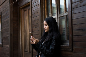 woman leaning on a window texting with her cell phone
