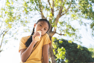 Fototapeta premium Portrait of little asian girl drinking milk in garden outdoor