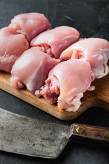 Fresh chicken thighs with meat cleaver, on black background