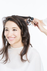 Fototapeta premium ヘアアイロンで髪を巻く女性