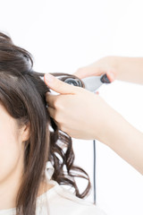 Naklejka premium ヘアアイロンで髪を巻く女性