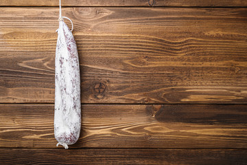 Longaniza fermented white sausage on light wooden background, top view with copy space
