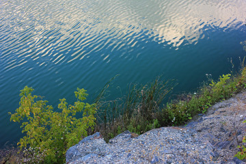 Mountain lake in the summer. Panoramic view on old flooded granite quarry with radon water. Landscape with rock stones, green trees and clean pond