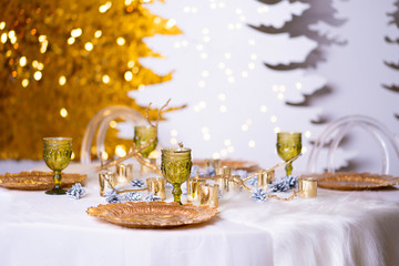 The festive Christmas table is decorated with branches of a Christmas tree, candles and garlands. Cozy home Christmas atmosphere.