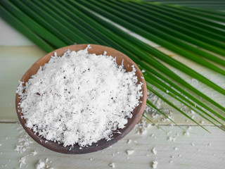Grated coconut in clay pot on wood background. Thai herbs concept.