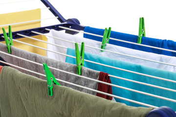 Clean clothes hanging on dryer against white background, closeup