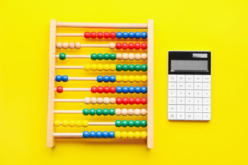 Calculator and abacus on color background