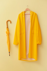 Raincoat and umbrella on color background
