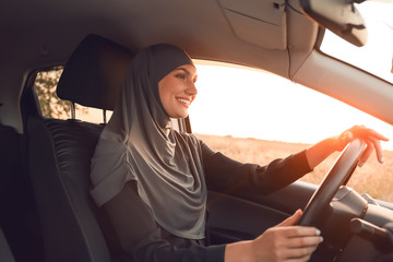 Young Muslim woman sitting in car