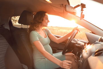 Young pregnant woman sitting in car