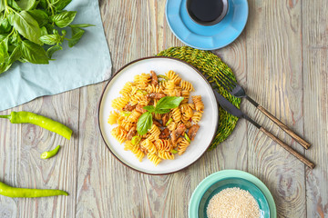 Plate with tasty pasta and chicken on table