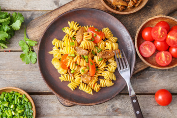 Plate with tasty pasta and chicken on table