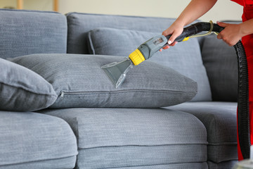 Dry cleaner's employee removing dirt from sofa in house