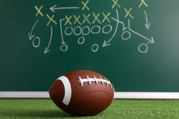 Rugby ball and scheme of football game drawn on chalkboard