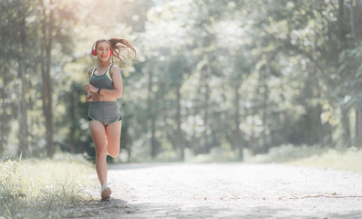 woman in sportswear and headset running outdoors in the park.