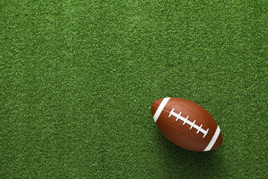 Rugby ball on green grass, top view
