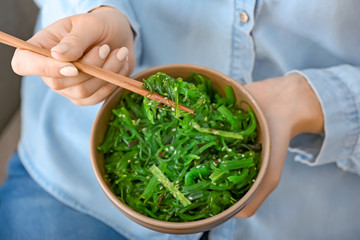 Woman eating tasty seaweed salad, closeup