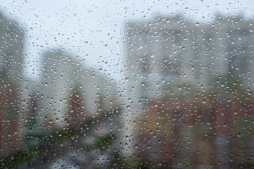raindrops on the glass. A modern residential complex is visible in the focus