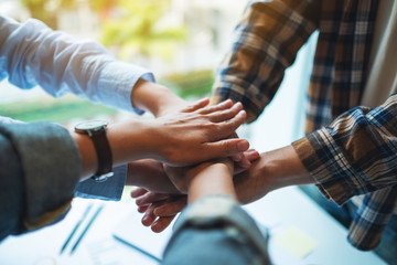 Closeup image of business team standing and joining their hands together in office