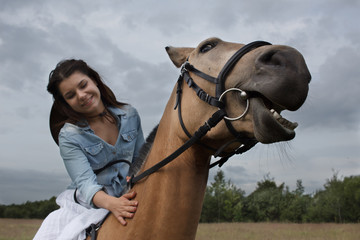 Obraz premium Young cow girl walking horse in green field. People and animal portrait. Horseback riding view. Active weekend