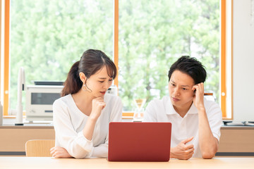 リビングでパソコンを見る夫婦・カップル