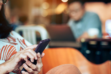 Hands of woman use smartphone and relax with beverage in coffee shop, where seats are spaced for social distancing during the Corona virus(COVID-19) epidemic.New normal lifestyle.Selective focus