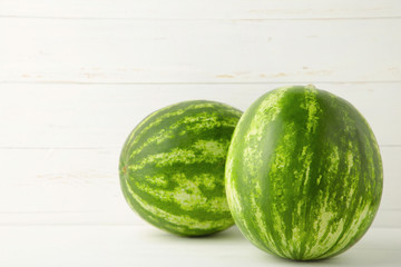 Two fresh watermelon on the white wooden background.