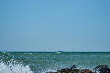 Image of the sea shore. In the background is a warship.