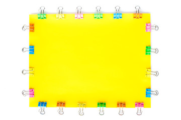 Blank yellow paper sheet with colored small paper clips attached around it, on white background