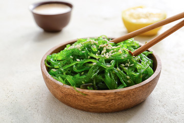 Plate with tasty seaweed salad on white background