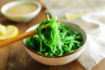 Bowl with tasty seaweed salad on table