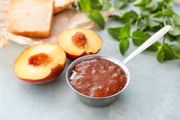 Bowl with tasty peach jam on color background