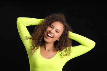 Young African-American woman with beautiful eyeshadows on dark background