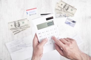 Man using calculator. Dollars, credit cards and document on the desk