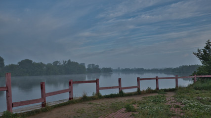 An abandoned pier on the river with crooked red columns